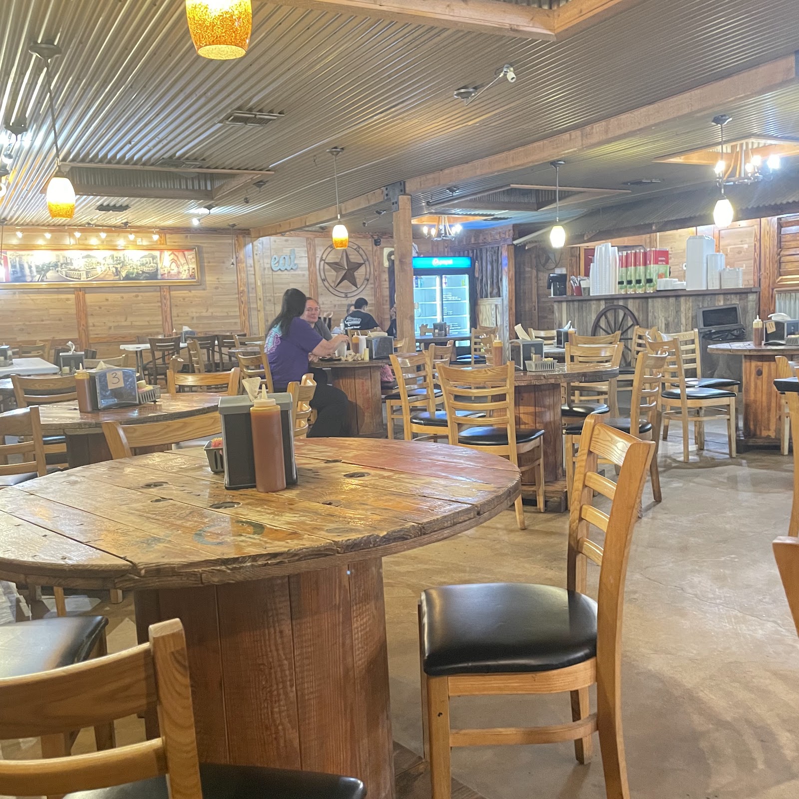 Dining room at Texas D Willie's Smokehouse with wood tables and corrugated tin ceiling